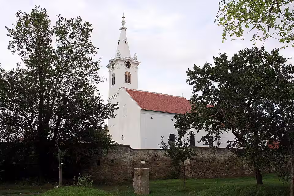 Pfarrkirche Zur Kreuzerhöhung zwischen Bäumen in Wulkaprodersdorf