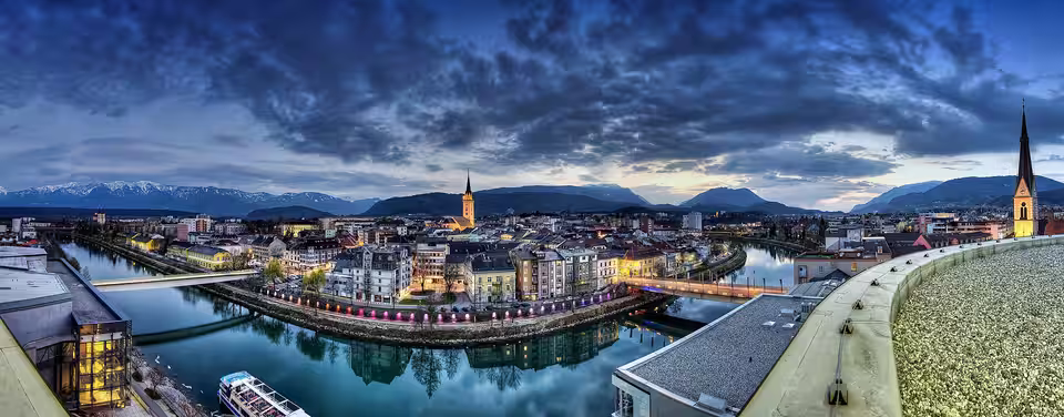 Abendpanorama von Villach mit Drau, Brücken und Kirchtürmen