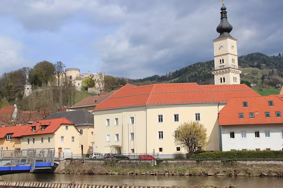 Häuser und Kirchturm am Flussufer in Wolfsberg