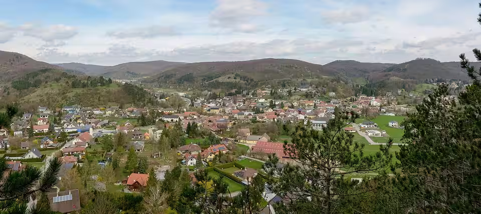 Panoramablick auf Alland zwischen bewaldeten Hügeln