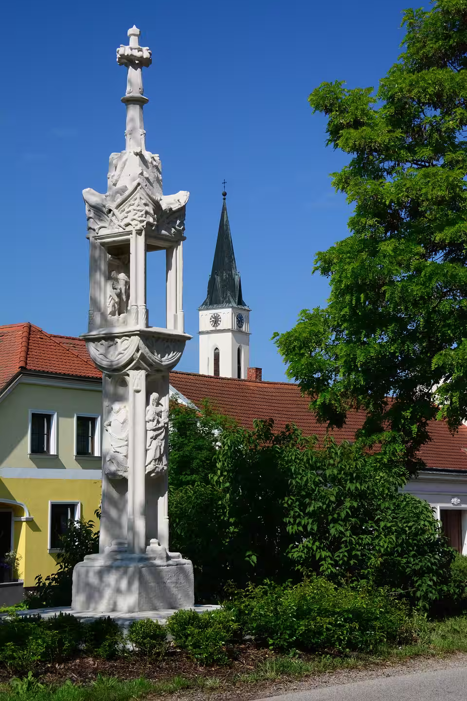 Historische Lichtsäule mit Kirche im Hintergrund in Guntersdorf