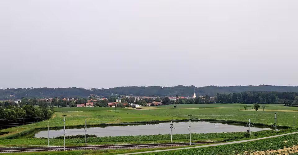 Blick über einen Teich und Felder auf Sankt Martin im Sulmtal