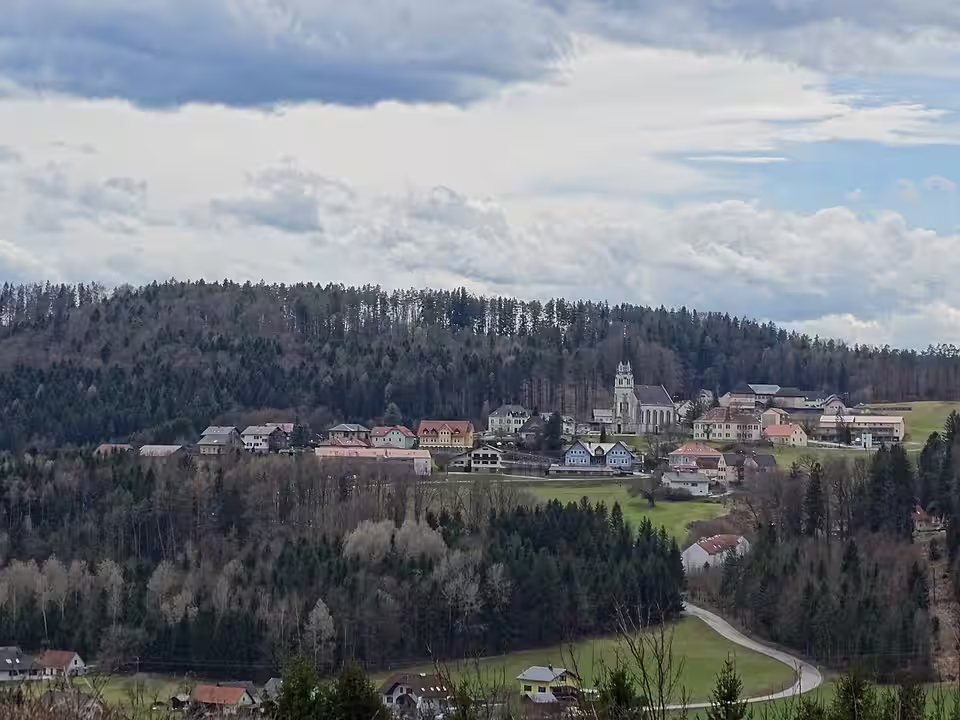 Sankt Bartholomä mit Kirche und Häusern vor einem bewaldeten Hang