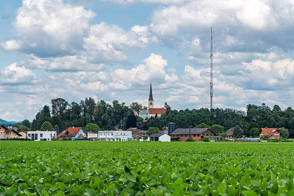Dobl mit Kirche und historischem Sendemast hinter einem Feld