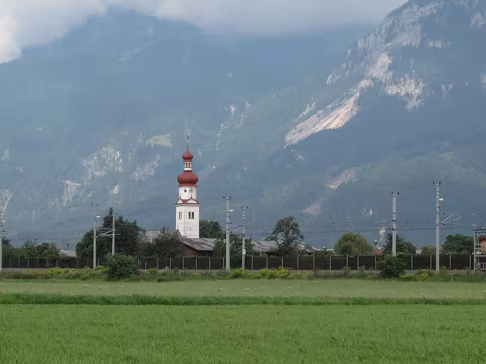 Kirchturm von Radfeld hinter grünen Feldern