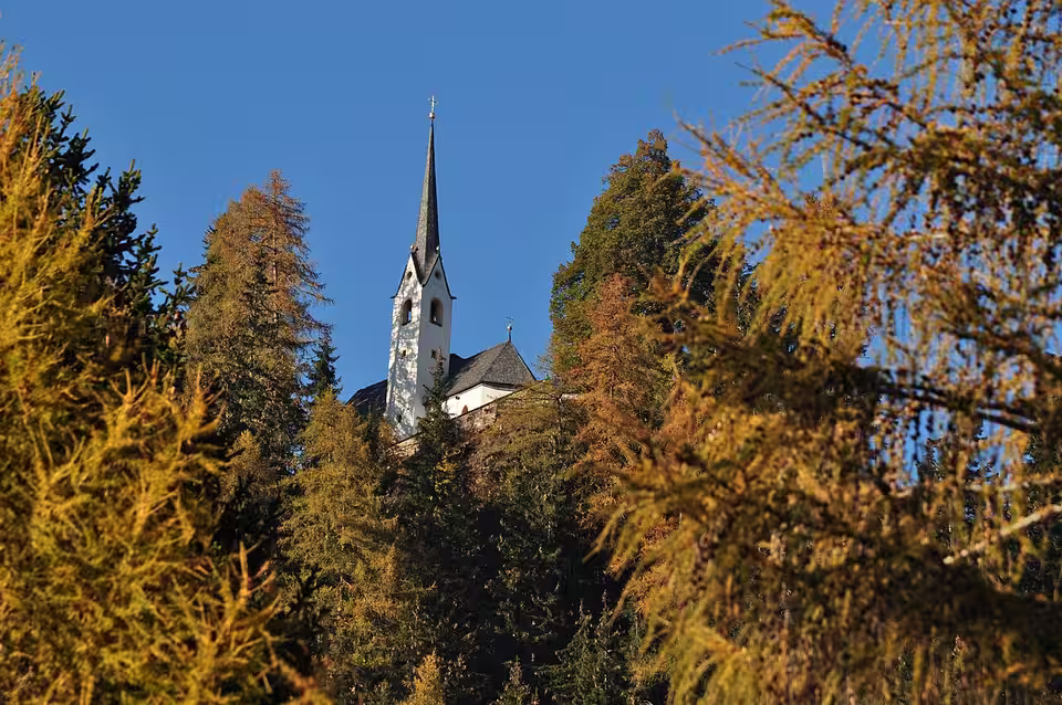 Sankt-Helenen-Kirche in Oberlienz zwischen herbstlichen Bäumen