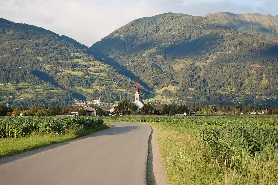 Straße durch Felder nach Tristach mit Kirche vor den Bergen